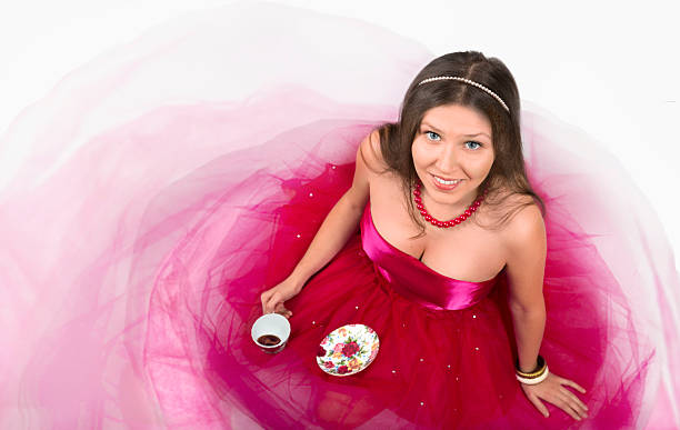 Cheerful young female smiling and holding a cup of coffeein a white background